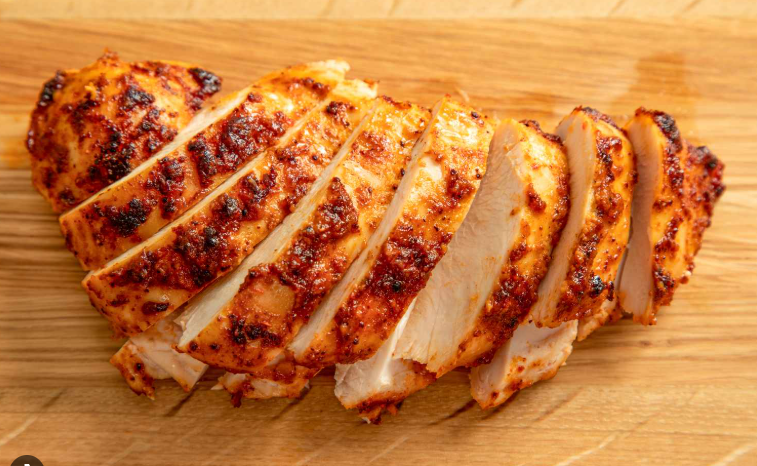 Sliced grilled chicken breast on a wooden cutting board